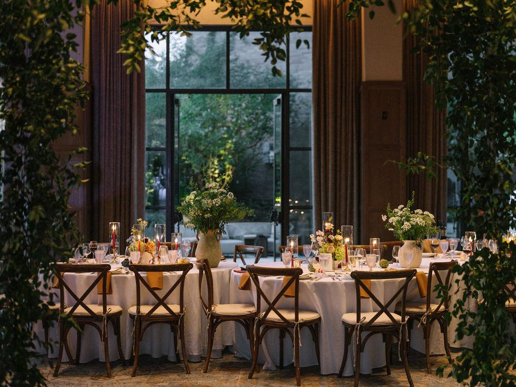 Reception room with tall windows, long wooden tables and fruit-laden autumn tablescapes