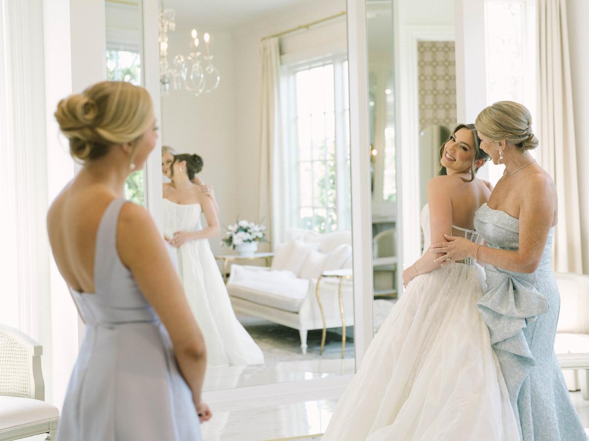 A bride and two attendants getting ready in a bright room