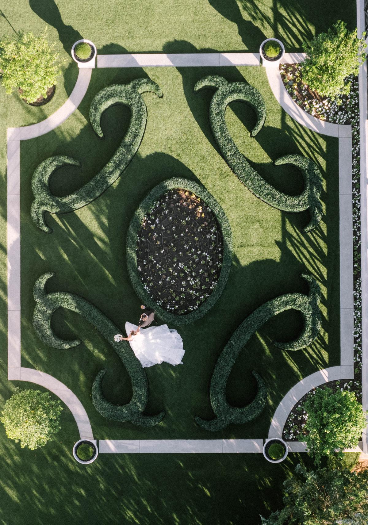 Aerial view of a couple walking through a formal boxwood garden
