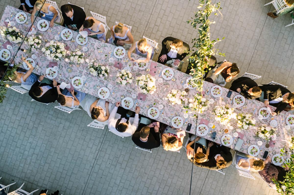 Overhead view of a long banquet table dressed in floral linens and lined with flowers