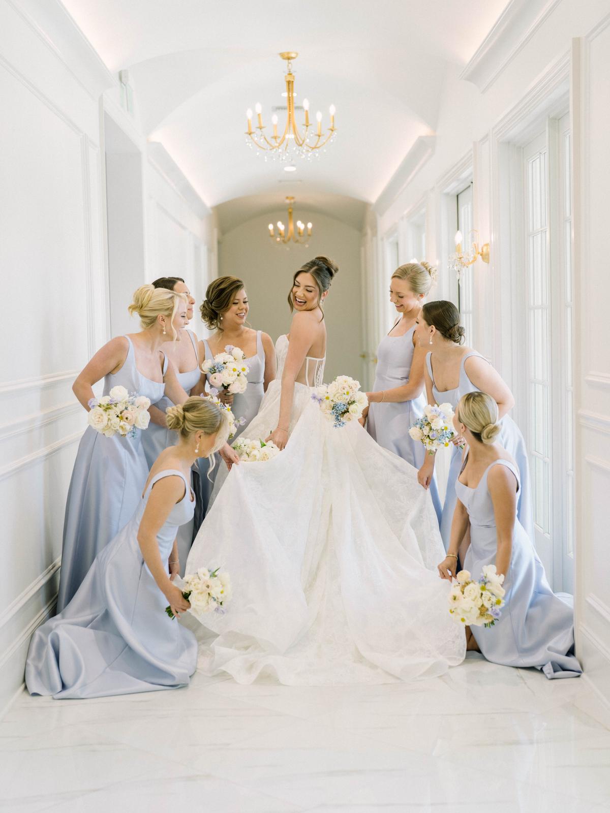 A bride and her attendants holding bouquets in a sunlit hallway