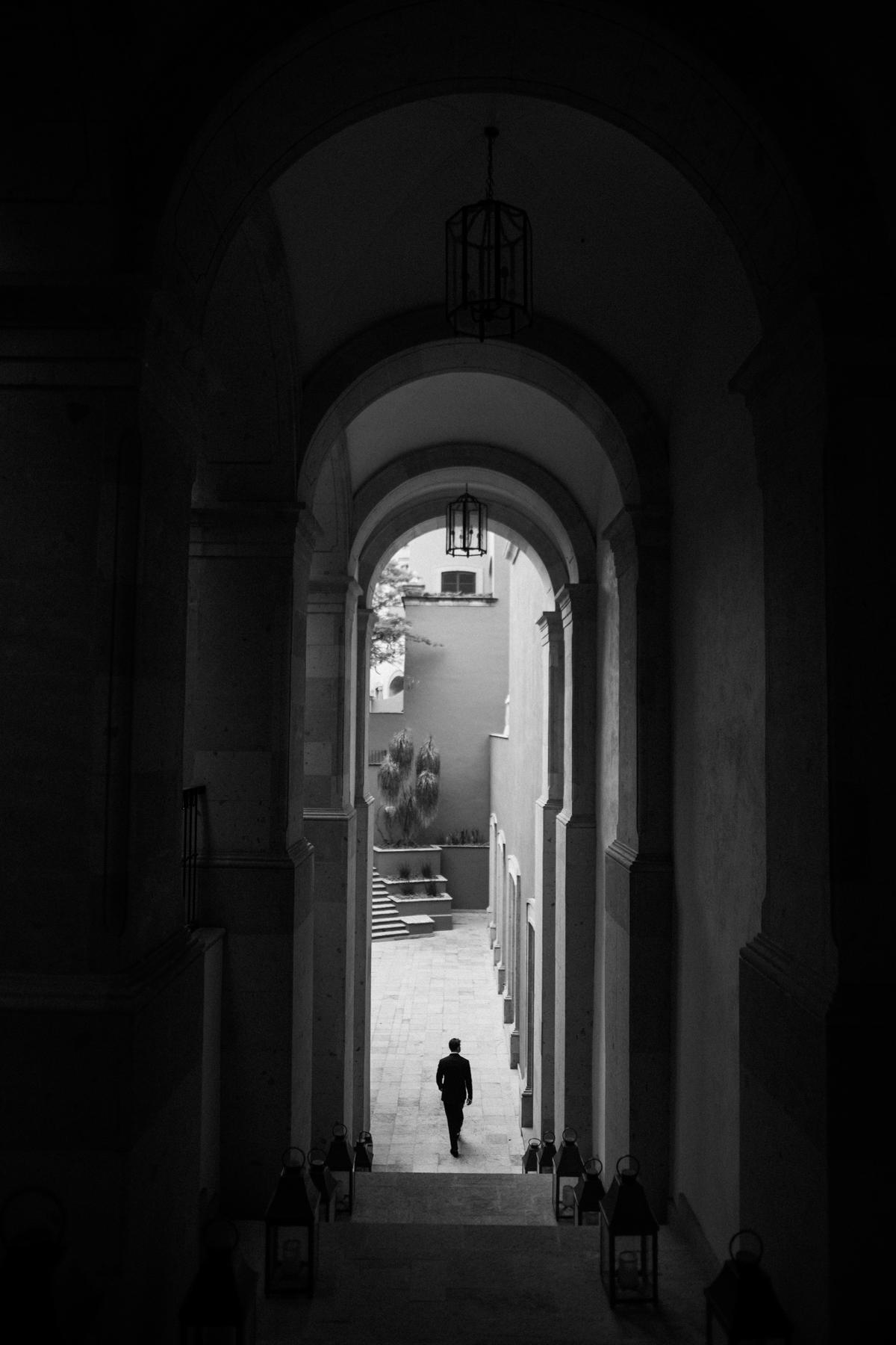 A long shadowed colonnade in black and white, receding to a distant figure in bright daylight