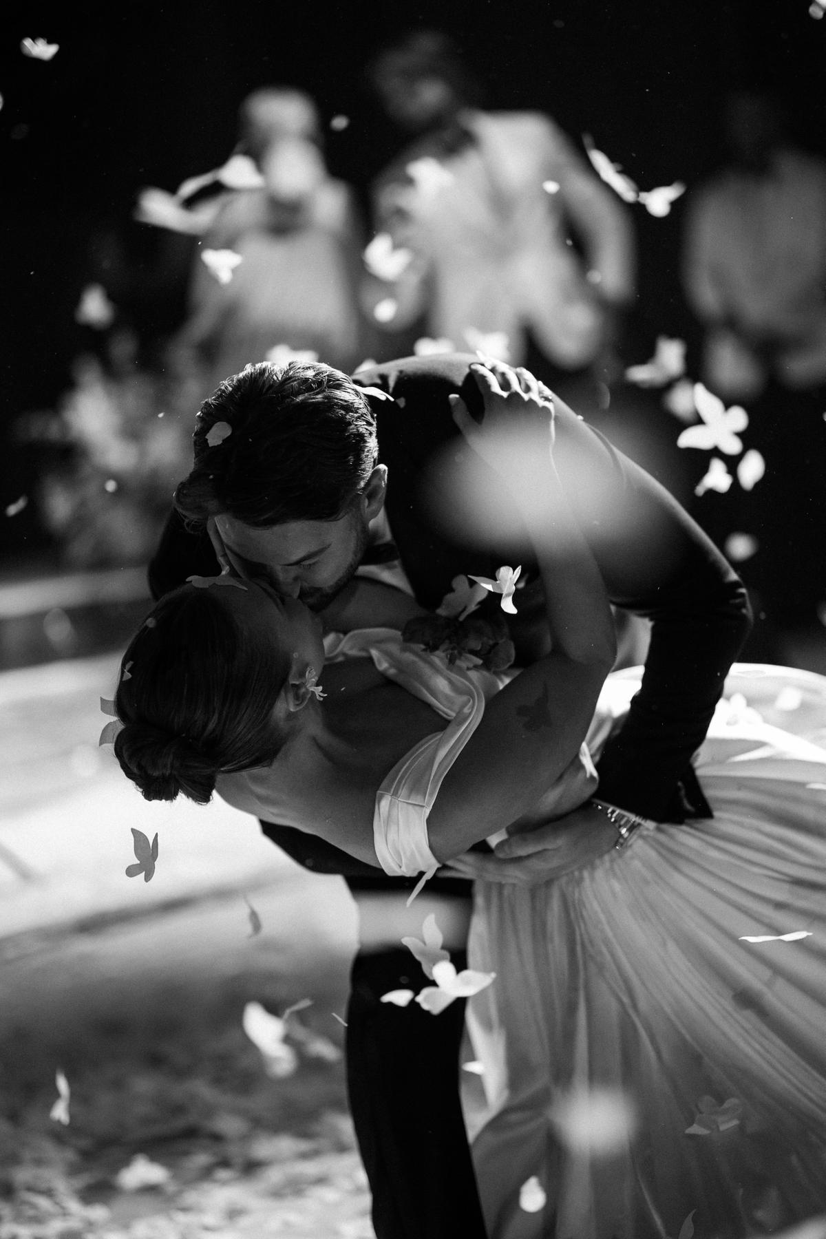 A couple dance closely in black and white as confetti falls around them