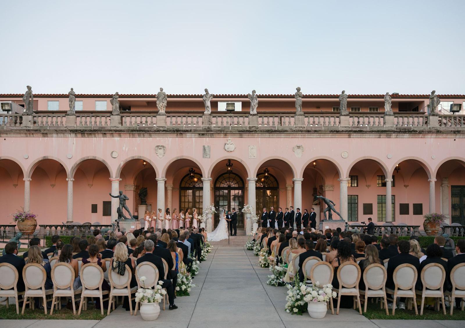 Daylight ceremony down the museum colonnade with rows of chairs and the couple at the altar