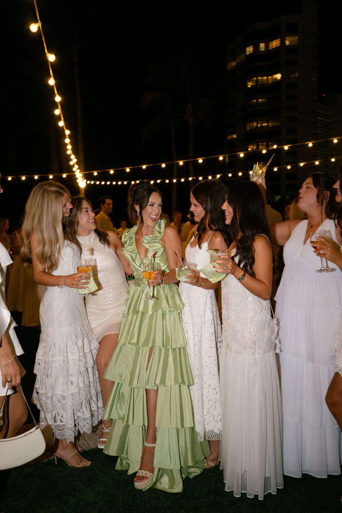 Guests in evening dresses celebrating together under string lights