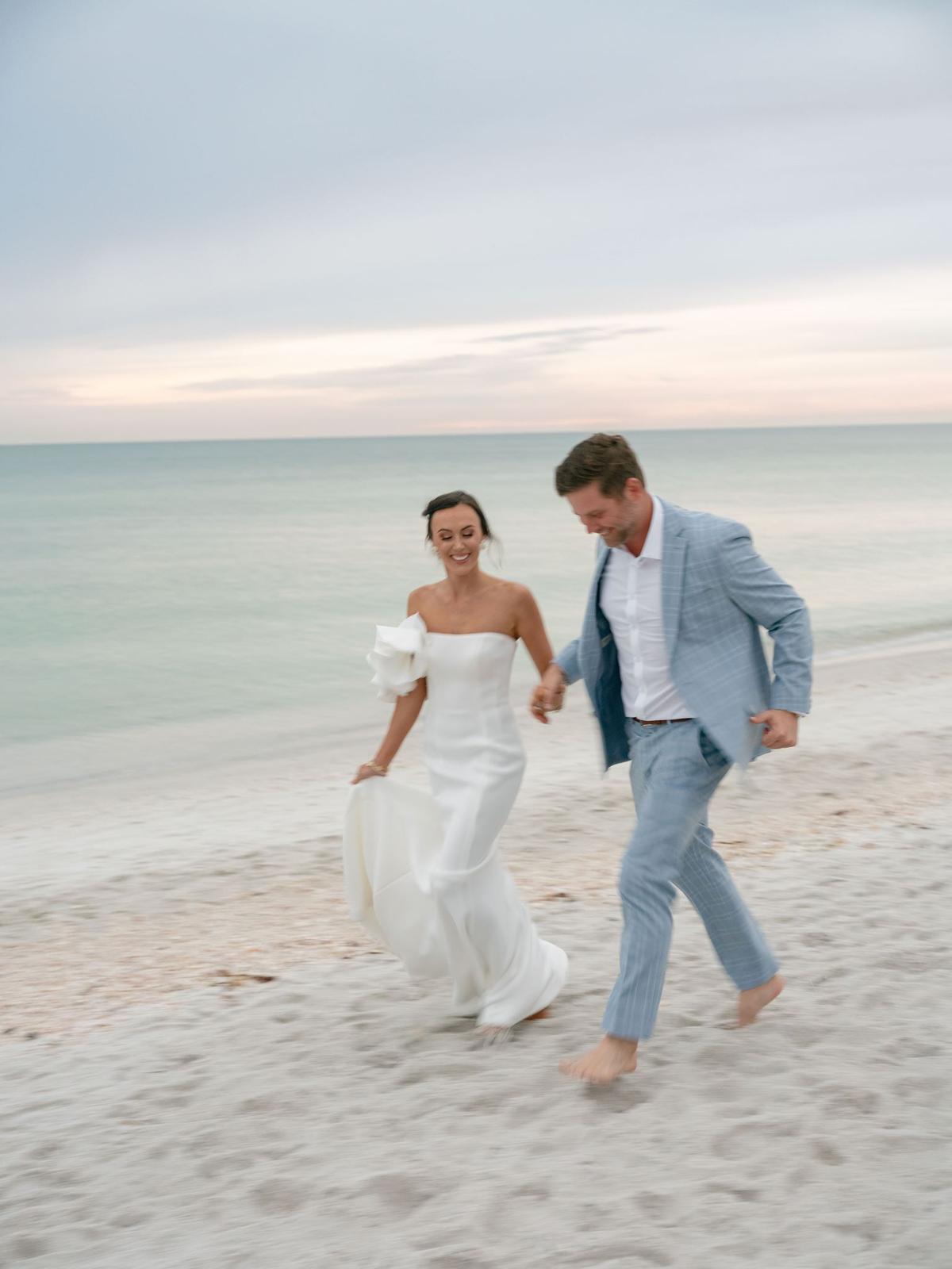 Couple walking barefoot along the shoreline at sunset
