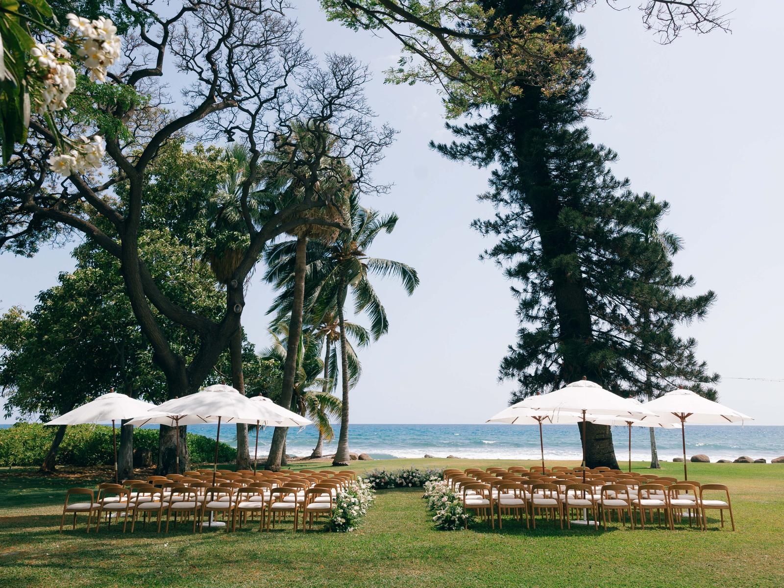 Long reception tables set under palm trees beside the ocean at a Maui wedding