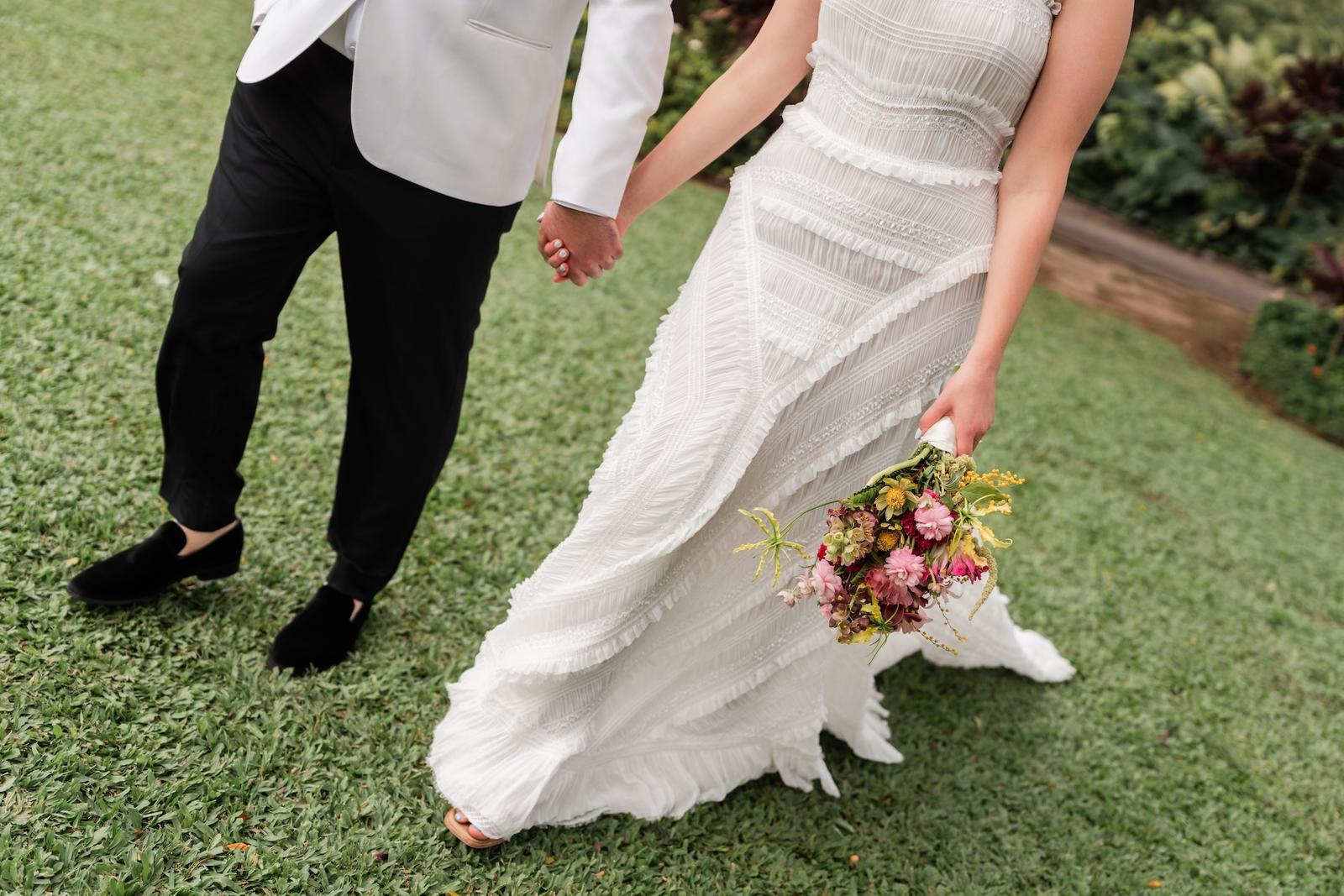The couple's hands and a tropical bouquet in blue and fuchsia