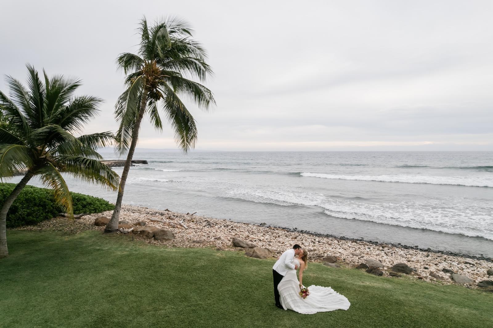 The couple walking along the rocky shoreline under a palm tree