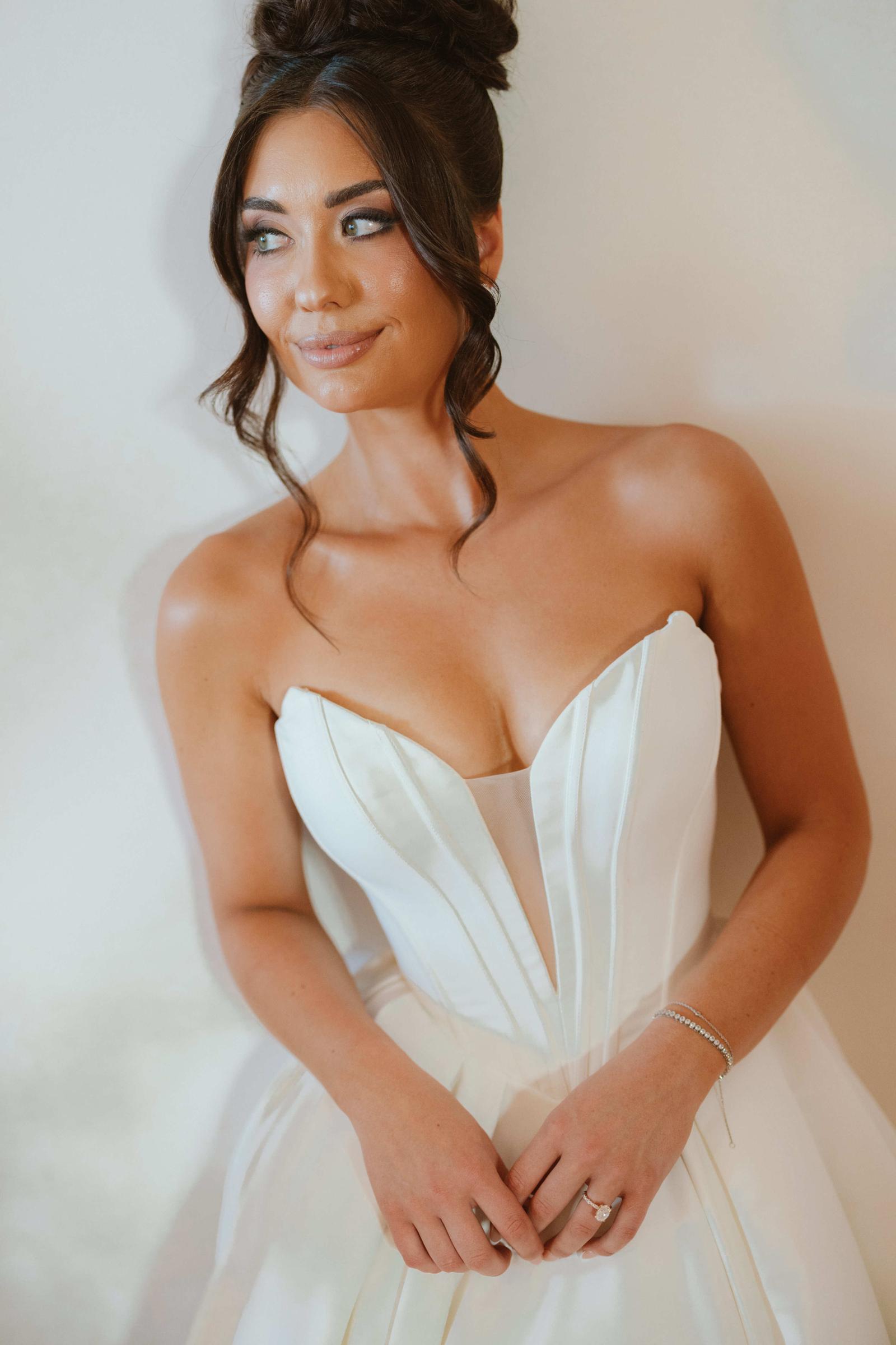 Portrait of a bride in a strapless white gown glancing over her shoulder