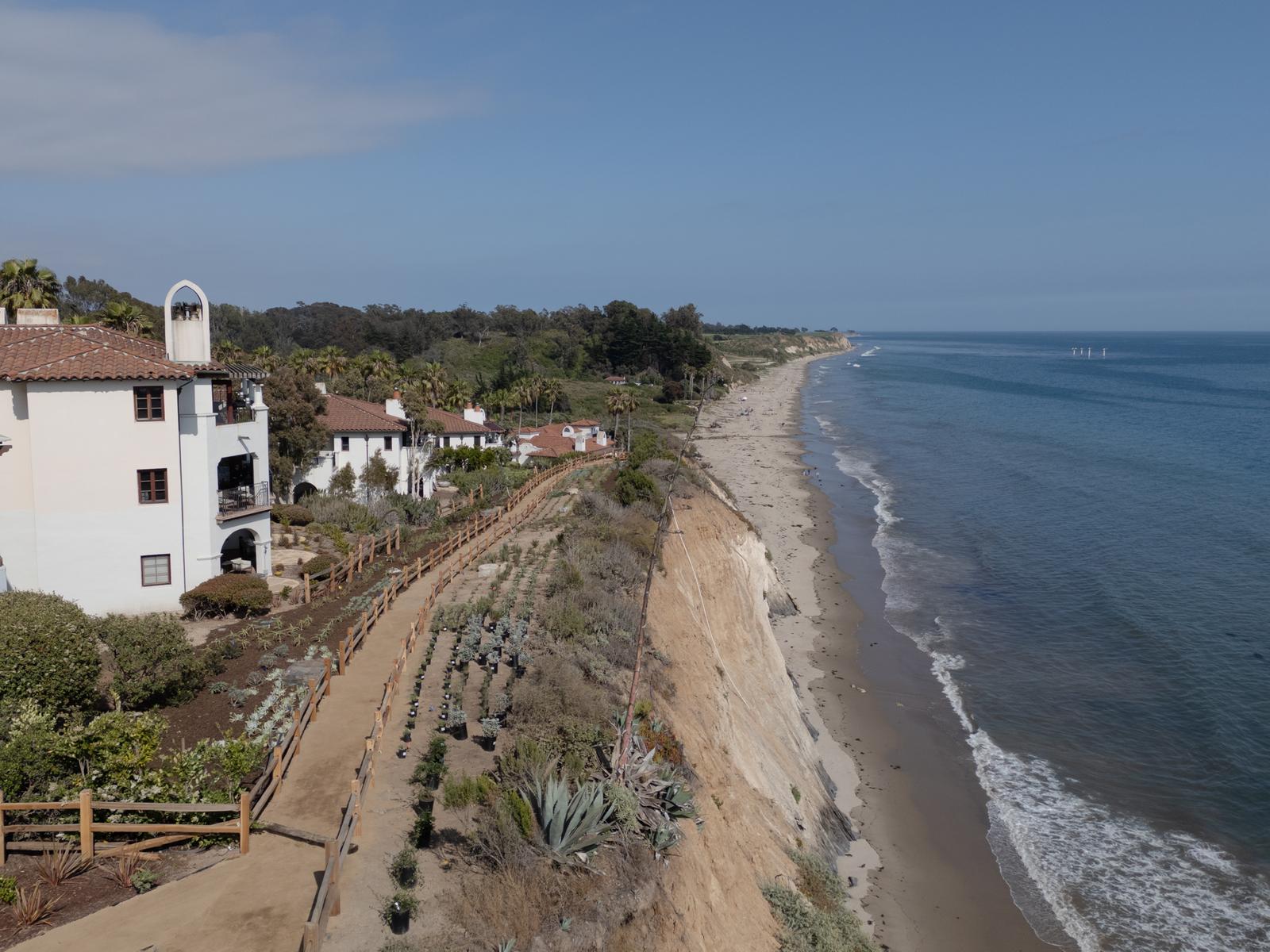 Aerial view of a white Spanish-style resort on a bluff above a long stretch of Santa Barbara coastline