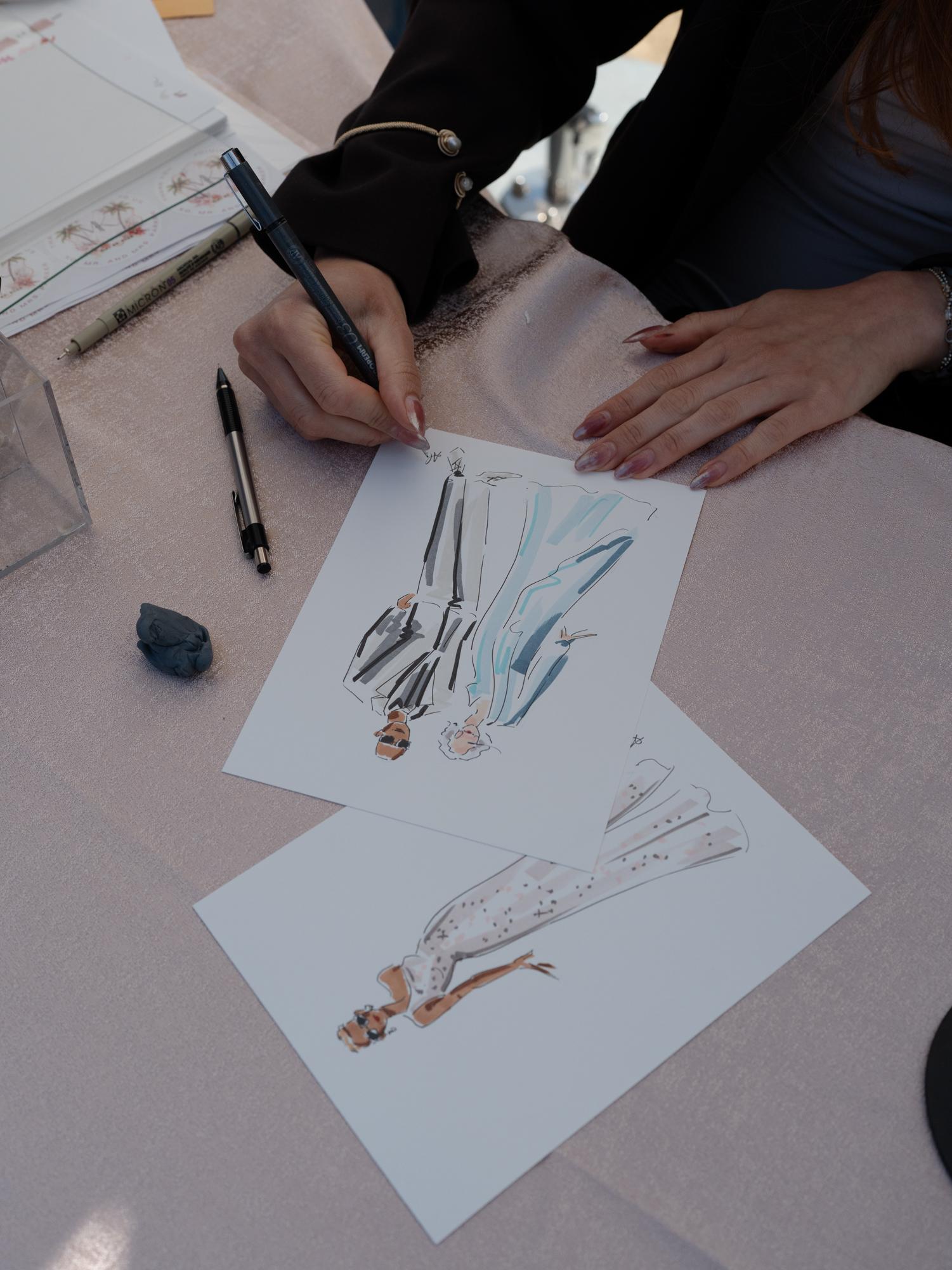 An illustrator sketches wedding guests by hand in pen and watercolor