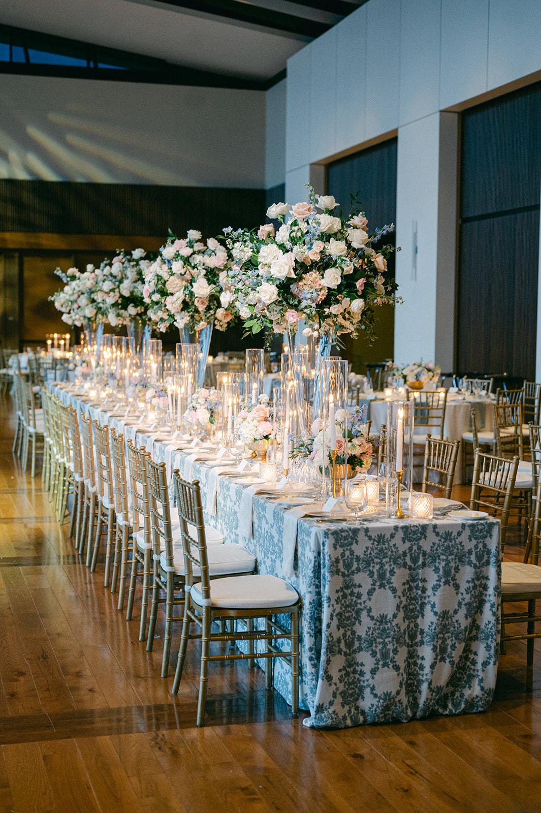 Long reception tables with blue patterned linens, candles and blush and blue florals